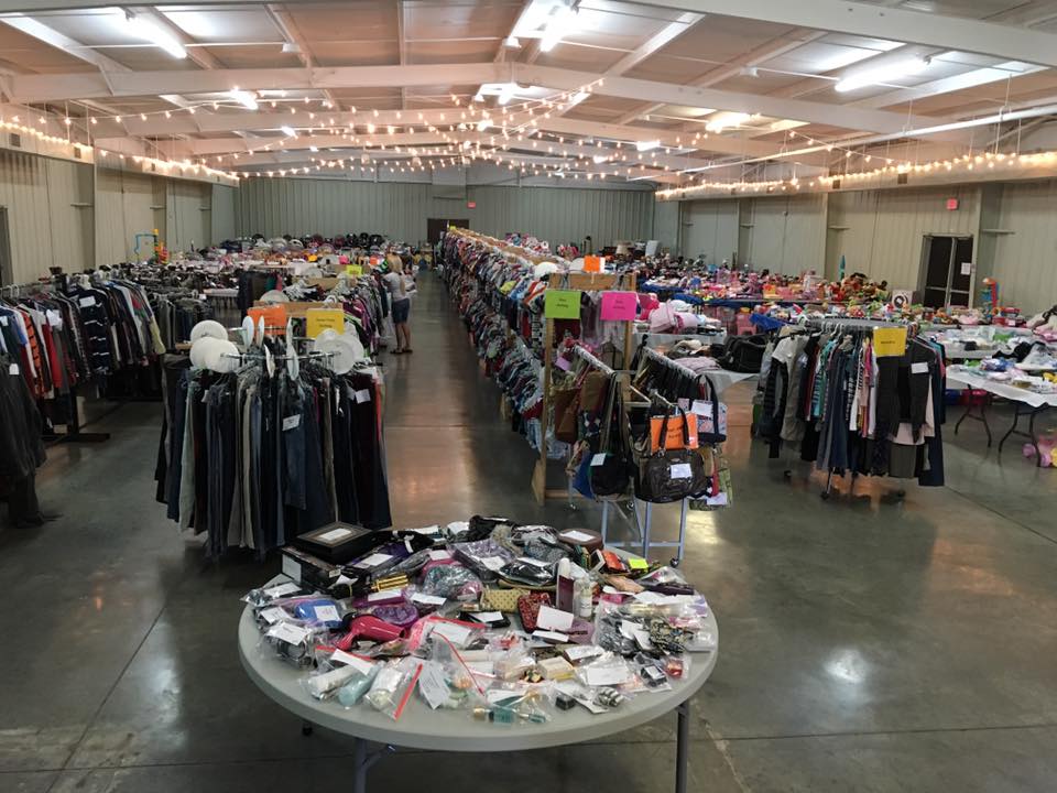 Racks of clothing,purses,tables with toys and beauty items on display in a large well lit room